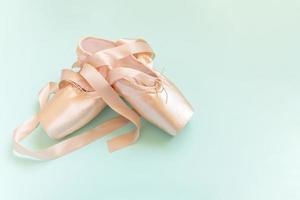 nuevos zapatos de ballet beige pastel con cinta satinada aislados en fondo azul. Bailarina de punta clásica para entrenamiento de baile. concepto de escuela de ballet. vista superior plana, espacio de copia foto