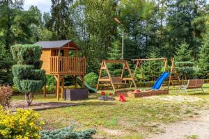 Empty modern wooden children playground set on green yard in public park in summer day. Funny toy land for kids. Urban exercise activities for child outdoors. Neighborhood childhood concept. photo