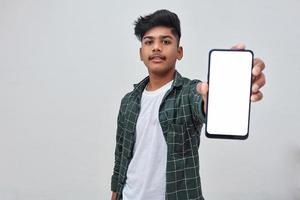 Young indian collage boy showing smartphone screen on white background. photo