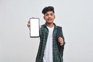 Young indian collage boy showing smartphone screen on white background. photo