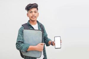 Young indian student holding file and showing smartphone screen on white background. photo