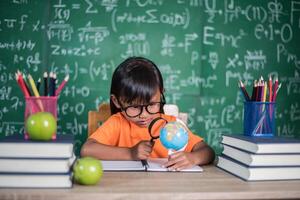 niño observando o estudiando el modelo de globo educativo en el aula. foto