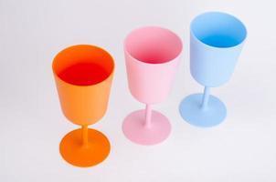 Colored plastic wine glasses on white background. photo