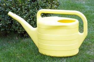 Yellow watering can for watering plants in garden.