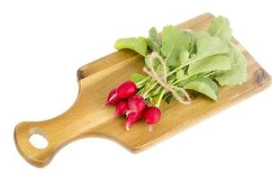 Bunch of fresh red radish on wooden cutting board for cooking. photo