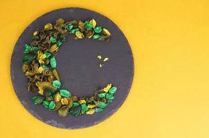 Creative flower composition in form of crescent of dry flowers and petals, green leaves. Top view, flat lay. photo