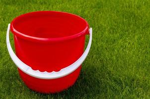Colored plastic garden buckets on background of green grass photo