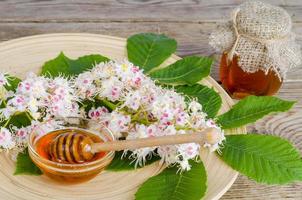 Delicious chestnut honey in glass on wooden surface. photo