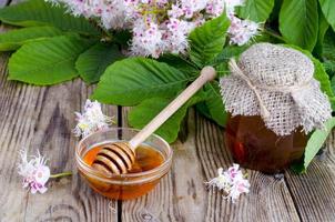fragante miel de castaño en tarro con flores de flor. foto