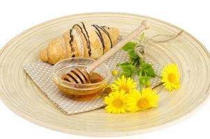 Fresh croissant, honey, yellow flowers. photo