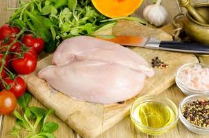 Fresh raw chicken fillet and vegetables prepared for cooking. photo