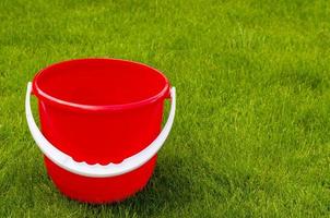 Colored plastic garden buckets on background of green grass photo