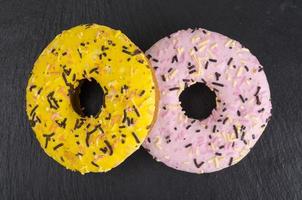 Homemade donuts with colored icing on black background. photo
