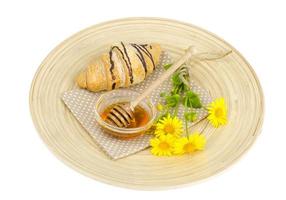 Fresh croissant, honey, yellow flowers. photo