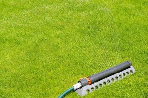 sistema de riego, riego por aspersión de agua sobre césped verde foto