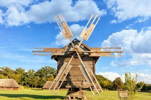 Large old wooden windmill against the backdrop of the village and the high blue sky. photo