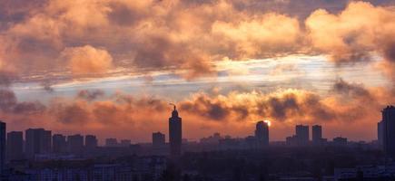 el smog de la ciudad está iluminado por los rayos del sol naciente temprano en la mañana. foto