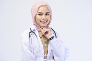 Female muslim doctor with hijab over white background studio. photo