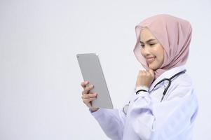 Female muslim doctor with hijab over white background studio. photo