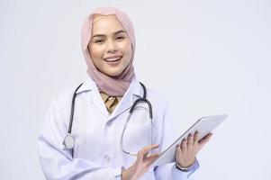 Female muslim doctor with hijab over white background studio. photo