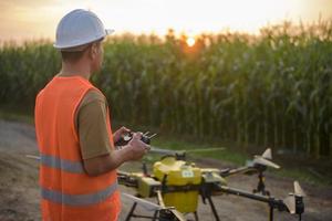 Male engineer controlling drone spraying fertilizer and pesticide over farmland,High technology innovations and smart farming photo