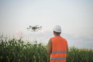 Male engineer controlling drone spraying fertilizer and pesticide over farmland,High technology innovations and smart farming photo
