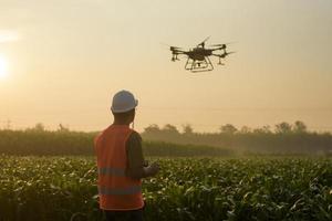 Male engineer controlling drone spraying fertilizer and pesticide over farmland,High technology innovations and smart farming photo
