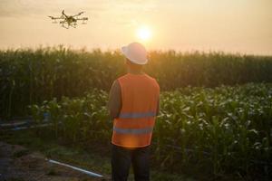 Male engineer controlling drone spraying fertilizer and pesticide over farmland,High technology innovations and smart farming photo