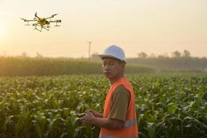 Male engineer controlling drone spraying fertilizer and pesticide over farmland,High technology innovations and smart farming photo