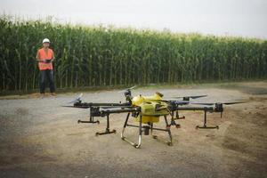 Male engineer controlling drone spraying fertilizer and pesticide over farmland,High technology innovations and smart farming photo