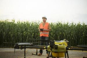 Male engineer controlling drone spraying fertilizer and pesticide over farmland,High technology innovations and smart farming photo