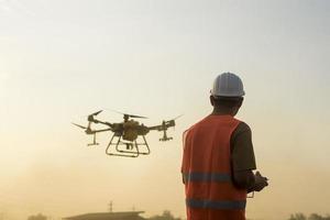 ingeniero masculino que controla la fumigación de fertilizantes y pesticidas con drones sobre tierras de cultivo, innovaciones de alta tecnología y agricultura inteligente foto