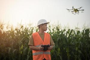 Male engineer controlling drone spraying fertilizer and pesticide over farmland,High technology innovations and smart farming photo