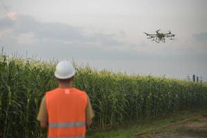 Male engineer controlling drone spraying fertilizer and pesticide over farmland,High technology innovations and smart farming photo