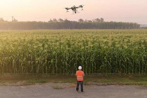 Male engineer controlling drone spraying fertilizer and pesticide over farmland,High technology innovations and smart farming photo