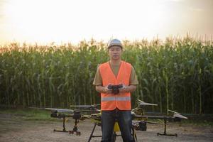 ingeniero masculino que controla la fumigación de fertilizantes y pesticidas con drones sobre tierras de cultivo, innovaciones de alta tecnología y agricultura inteligente foto