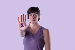 Young woman making the hand stop sign against lilac studio background. photo