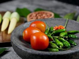 cayenne pepper and tomatoes in a stone mortar. tomato sauce recipe. food cooking concept photo