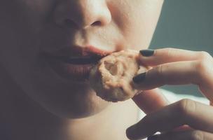 young woman eating a cookie in studio shot photo