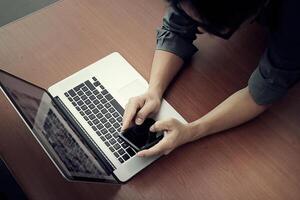 top view of businessman hand working with new modern computer and smart phone and business strategy on wooden desk as concept photo