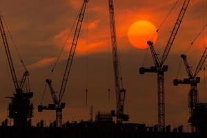 puesta de sol y silueta de la grúa en funcionamiento foto