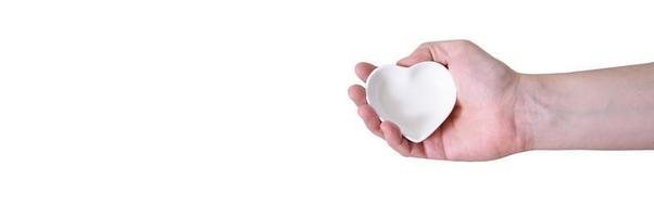 una mano con un platillo en forma de corazón sobre un fondo blanco. foto
