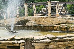 fountain and bridge of stone tiles in the Park. a decorative pond outdoors photo