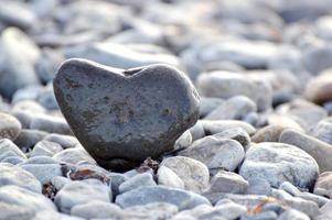 Heart shape stone against background of beach. Summer sunny day. Love, wedding and Valentine day concept. Finding beautiful and interesting stones. Beach vacation photo