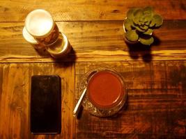 A cup of coffee and smartphone on wooden table in cafe photo