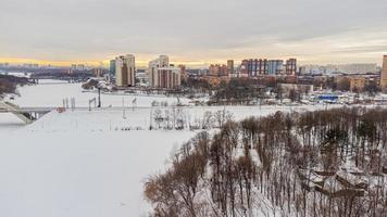 There is a view from a height using a quadcopter along the icy river and high-rise buildings photo