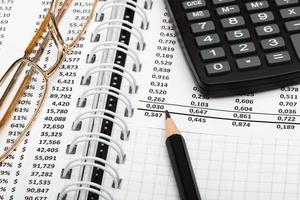 Financial report, pencil, calculator, glasses and paper with numbers on the table in the office. A paper sheet full of business data. Accounts number and the data. Business documents. Close-up