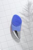 cepillo facial sónico azul sobre baldosas blancas con gotas de agua foto
