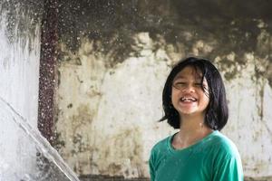 A  little girl playing water splashing with a hose. photo