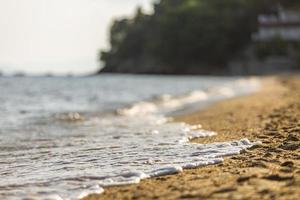 Soft Wave Of Blue Ocean On Sandy Beach at Sunset. Background. Selective focus. photo